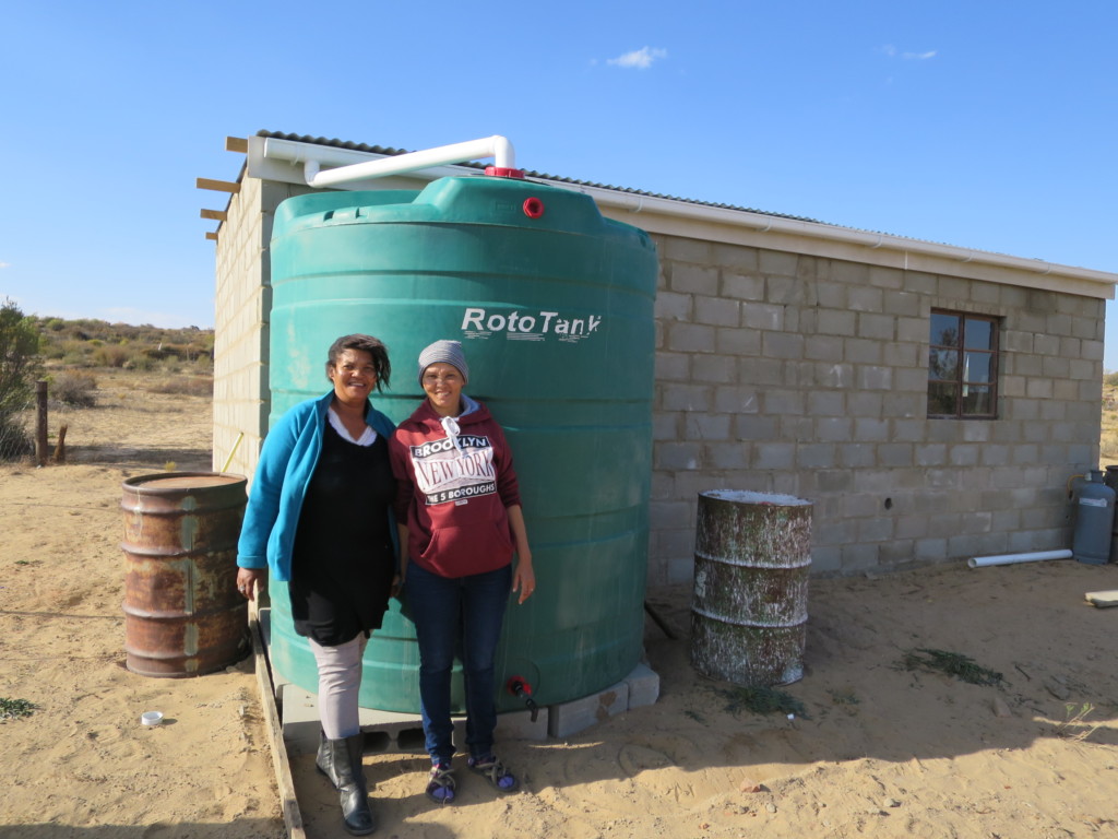 Katriena Fortuin with rainwater harvesting tank to support her family in managing water scarcity in South Africa. Photo by Siya Myeza, Environmental Monitoring Group