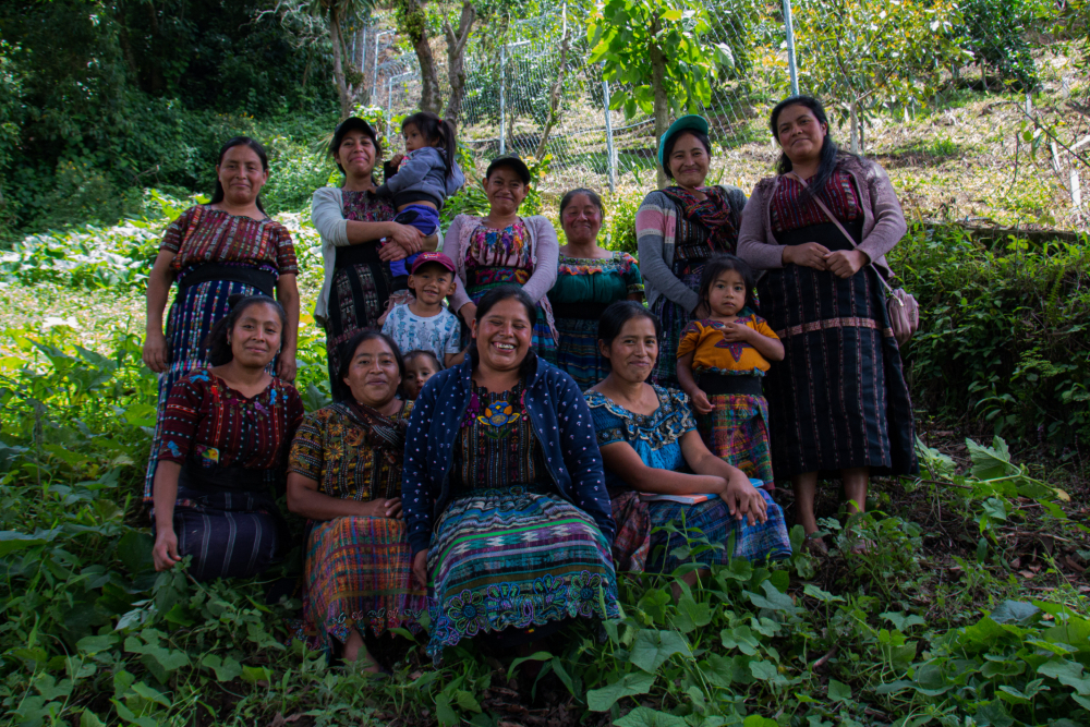 A group of women and girls stand in a field smiling and posing for a photo.